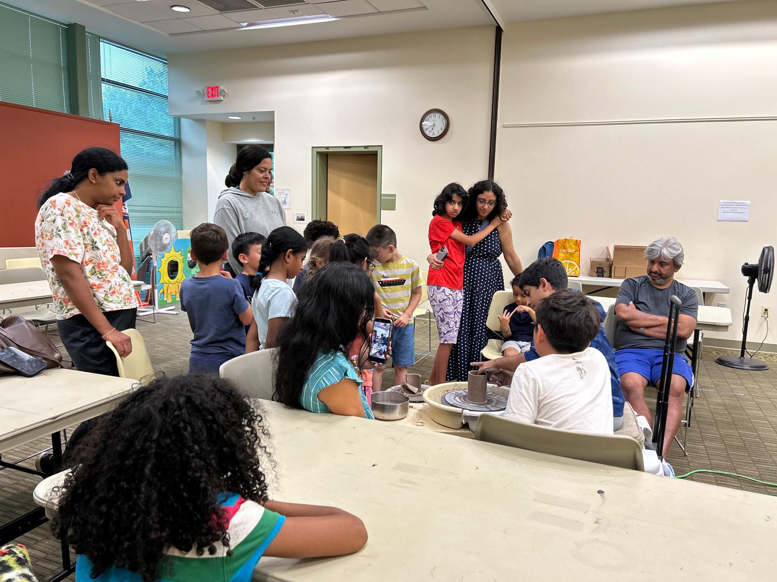 Children seated in a library meeting room during a pottery science session